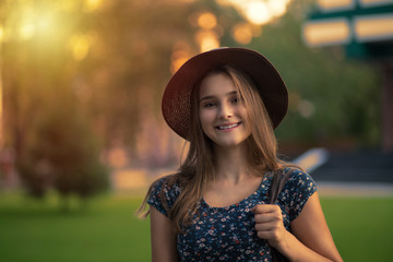 Happy in the city in evening. Young mixed woman with long hair style smiling in urban background black girl wearing casual blue dress with flowers and brown hat.