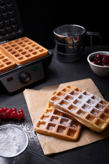 Classic golden waffles with powdered sugar in a composition on stony worktop 