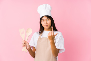 Young chinese chef woman isolated pointing with finger at you as if inviting come closer.