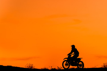 Obraz na płótnie Canvas Black silhouette Motocross rider on a motorcycle in front of colorful sunset