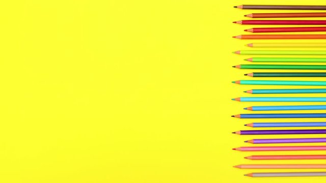 Colored crayons moving alternately on right side of yellow background - Stop motion 