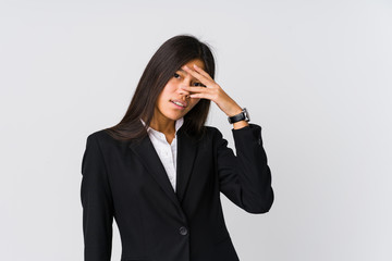 Young asian business woman blink at the camera through fingers, embarrassed covering face.