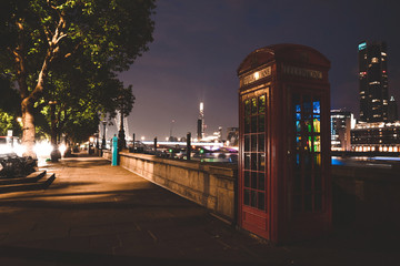 Quiet night in London. Classical red telephone booth standing by the river Thames.
