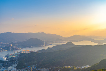 Nagasaki cityscape panorama view from Mt Inasa observation platform deck in sunny day sunset time with blue sky background, famous beauty scenic spot in the world. Nagasaki Prefecture, Japan