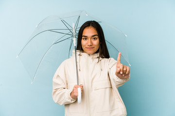Young asian woman holding a umbrella showing number one with finger.