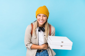 Young caucasian woman holding pizzas isolated laughing and having fun.
