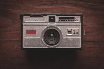 Old and worn photo camera from the 60s on rustic wooden table