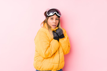 Young caucasian woman wearing a ski clothes in a pink background scared and afraid.