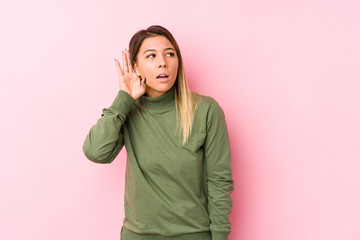 Young caucasian woman posing isolated  trying to listening a gossip.