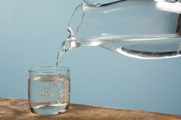 person filling a cup of water with a jar.