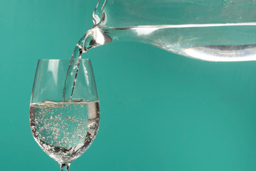 person filling a cup of water with a jar.