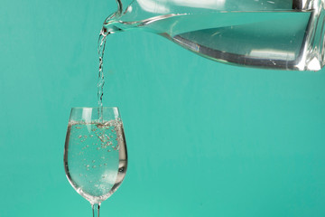 person filling a cup of water with a jar.
