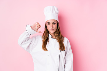 Young caucasian chef woman isolated showing a dislike gesture, thumbs down. Disagreement concept.