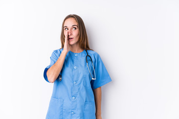Young nurse woman isolated is saying a secret hot braking news and looking aside