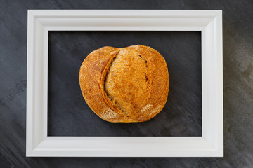 Sourdough wheat handmade bread in a white frame on a black background. Design of a bakery, cafe, restaurant, kitchen. Horizontal shot. Close up. Handmade food with soul. Bakery business.