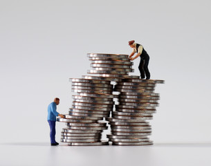 Two miniature men stacking coins.