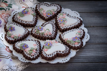 Heart shaped chocolate cookies decorated with royal icing glaze and flowers
