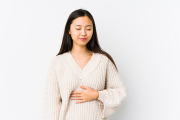 Young chinese woman isolated touches tummy, smiles gently, eating and satisfaction concept.