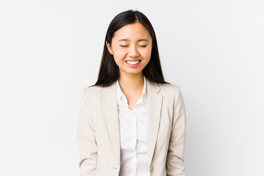 Young chinese business woman isolated laughs and closes eyes, feels relaxed and happy.