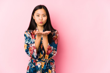 Young chinese woman wearing a kimono pajama isolated folding lips and holding palms to send air kiss.
