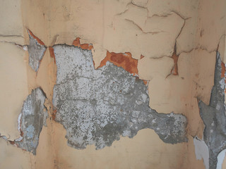 Old cracked beige wall in peeling stucco. Cracks on the city wall. Ancient buildings.