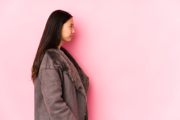 Young chinese woman wearing a coat isolated gazing left, sideways pose.
