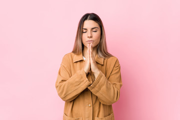 Young caucasian woman isolated holding hands in pray near mouth, feels confident.