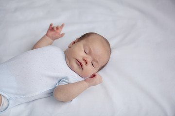 baby, newborn baby, cute blue-eyed, dark hair, baby 1 month, lying on a white bed