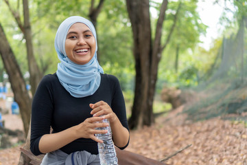 Malay Muslim lady wearing hijab outdoor resting and drink water
