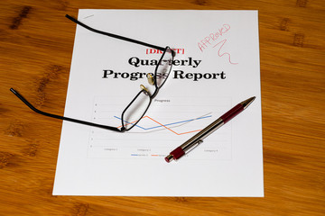 Glasses and a pen on a report with notations on the desk.  Plenty of room for copy.  Paperless Office is an elusive idea for many still.