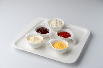 Set of assorted snack sauces isolated on white background: sour cream, mayo, mustard, ketchup and bbq sauce