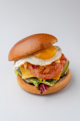 Hot mouthwatering burger with sunny side up egg isolated on white