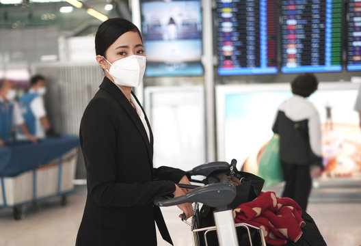 women withher luggage and trolley is wearing medical face masks to protect themselves from pollution, germs and coronavirus at the airport.