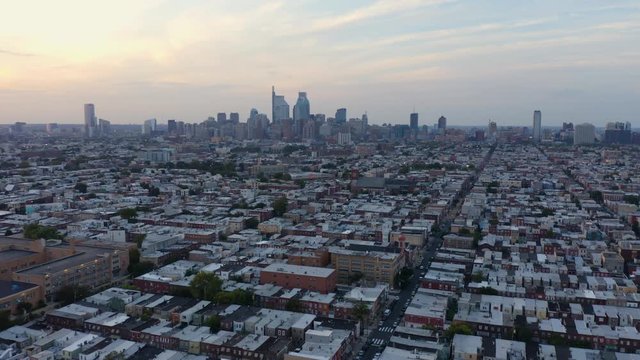 Aerial forward tilt up, Philadelphia city skyline in soft light at sunset