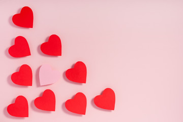 Valentine's day. Red paper hearts with shadow on pink surface.