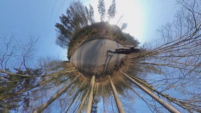 Man Riding Longboard Skateboard on Asphalt Road in Forest Tiny Planet View