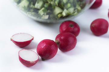 radish on a white background lies on a table, next to a cup with cucumbers