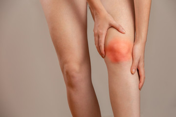 Bone pain or knees around the knee. The girl's hand is holding the knee area. Redhead woman.