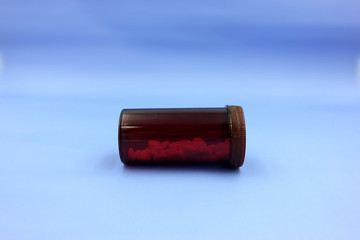 Close up, side view of medicine bottle in transparent brown colour made of plastic, horizontal angle. A packaging for medication purpose. Pill bottle isolated on blue background with copy space.