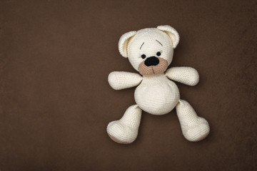 Top view of a small white bear cub lying on a brown background.