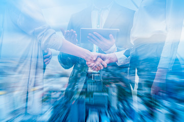 Double exposure businessman handshake to show cooperate in business with city scape building ...