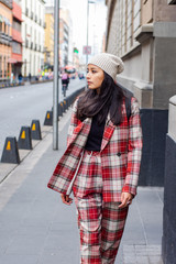 Fototapeta premium attractive woman walking down the street wearing a plaid suit and a hat