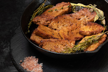 Roasted seitan in cast iron pan with various herbs and spices