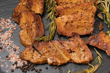 Roasted seitan steaks with herbs and spices on slate plate