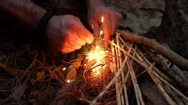 Survivalist Starting Fire with Flint and Steel in the Woods