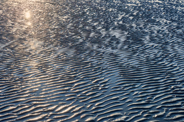 texture of wet sand on a beach during low tide.