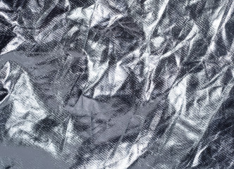 Silver crumpled textile, close up view. Vintage silver fabric, an abstract background. Texture of...