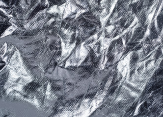 Silver crumpled textile, close up view. Vintage silver fabric, an abstract background. Texture of crumpled textile. Background for wallpapers and banners