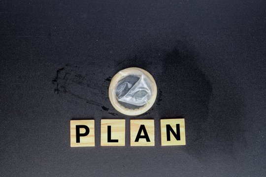 Condom and wooden block written PLAN for family planning concept.