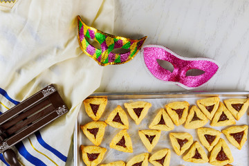 Jewish cookies Haman ears for Purim with mask, tallit and noisemaker.
